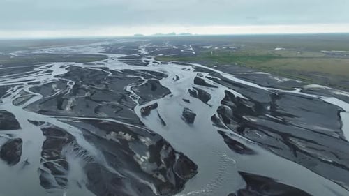 High angle panning shot showing a braided river flowing across a volcanic landscape, Iceland
