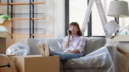 Woman on phone amidst moving boxes in home