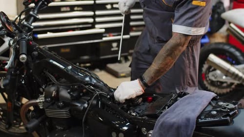 Mécanicien tatoué démolissant le compartiment moteur d'une moto