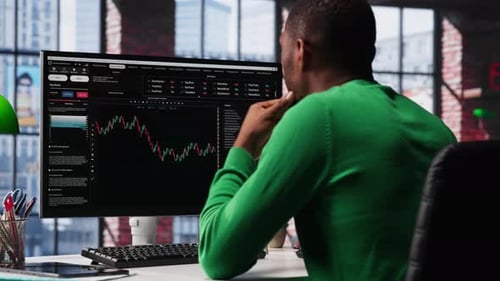Man Analyzes Stock Charts on Computer