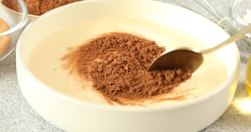 Mixing Cocoa Powder into Batter in White Bowl