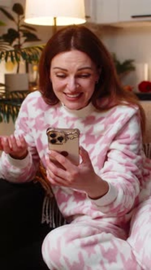 Excited Woman Looking at her Phone Indoors
