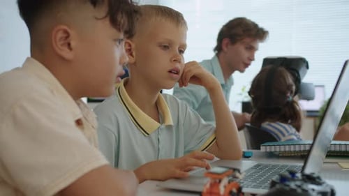 Des garçons apprennent à écrire du Code de programmation sur un ordinateur portable lors d'un cours d'informatique