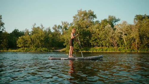 Woman Balancing on Stand Up Board and Paddling on Lake
