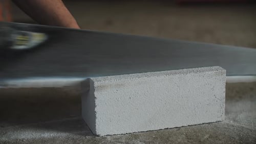 Builder Sawing White Brick Block with Hand Saw