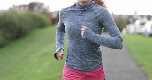 Woman Jogging on Path in Green Urban Park