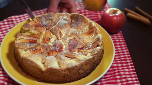 Cutting apple pie on plate with knife