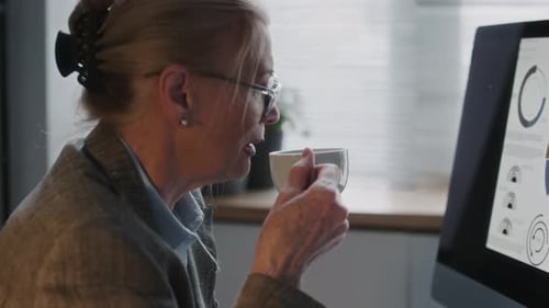 PDG d'une femme mature analysant les données financières et prenant une tasse de thé