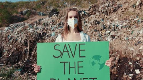 Young Woman Holding Save the Planet Sign at Dump