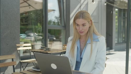 Businesswoman Smiling During Remote Video Call In Urban Outdoor Cafe