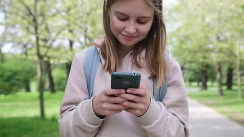 Cute Little Girl Using Smartphone In Park
