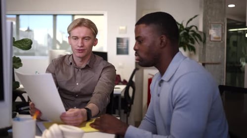 Coworkers discussing documents in modern office