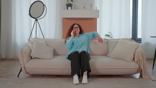 Woman Talking on Phone on a White Sofa in a Living Room