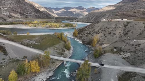Car crossing a bridge over a turquoise mountain river