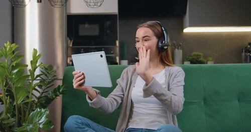 Feliz joven caucásica que sostiene una tableta digital sentada en el sofá de su casa. Dama sonriente