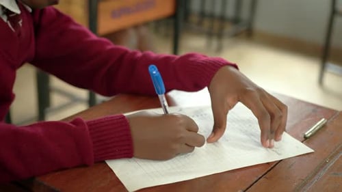 African Boy Writing Notes In Classroom At School - Close Up