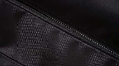 Person opening a backpack zipper to to put hand sanitizer into the bag.