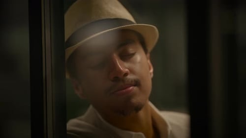 Man Resting by Window Wearing Fedora