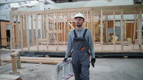 Construction Worker Walks with Toolbox and Drill Indoors
