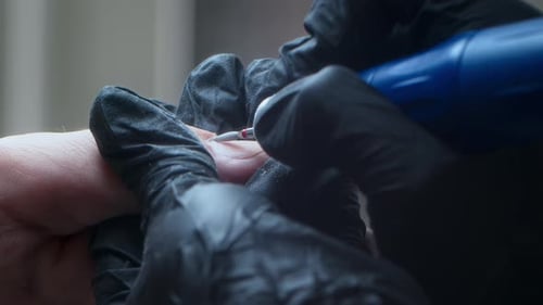 Manicurist Using Drill on Fingernail Close Up