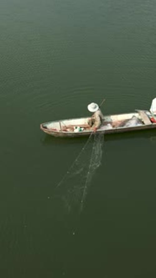 Lone Fisherman in His Small Boat Spreading the Nets in the Great River of Vietnam