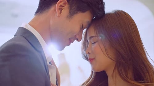 Asian handsome groom trying on wedding gown with his fiance in studio.