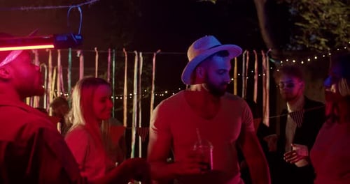 Festive friends celebrating at night with colored lights