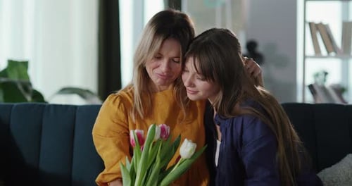 Mother and Teen Daughter Embrace With Flowers