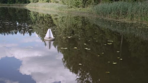 El barco navega junto a una pequeña boya blanca en el estrecho lecho del río con un punto de vista de costa verde