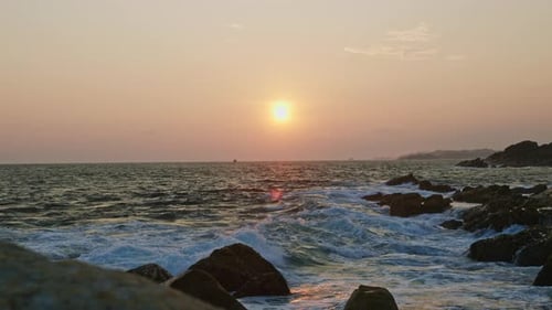 Sunset Horizon Over Tumultuous Ocean Waves Rocks at Foreground Vibrant Sky Meets Sea at Dusk