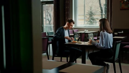 Date in the hotel restaurant dinner man and woman drink white wine in glasses and taste food
