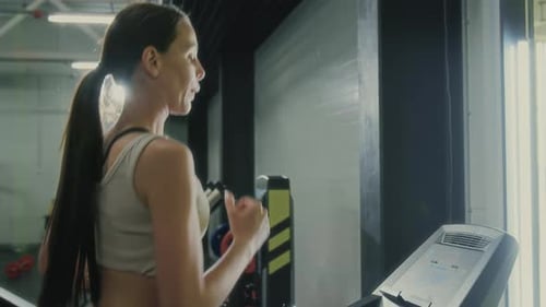 Woman Running on Treadmill in Modern Gym Surrounded by Fitness Equipment