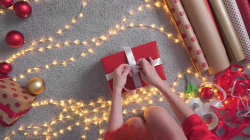 Woman Tying Bow on Christmas Gift From Above