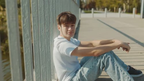 Sitting Casual Portrait of a Young Man Enjoying a Sunny Day Outdoors