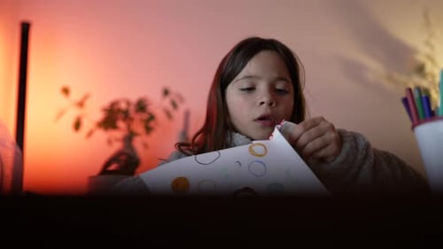 Creative child cutting paper with scissors, artistic little girl engaged in play by herself