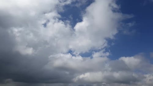 Blue summer sky with dense thick rain clouds moving across the heavens. Fast cloud formation and mov