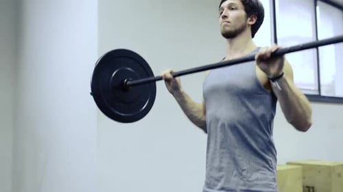 Young Muscular Man in Gym Lifting Heavy Barbell Active