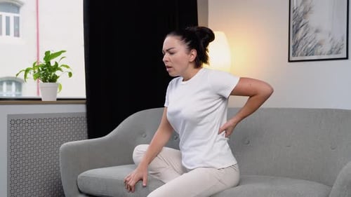 Woman on Couch Experiencing Lower Back Pain