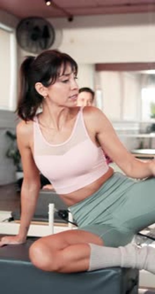 Woman Stretches on Pilates Machine with Instructor