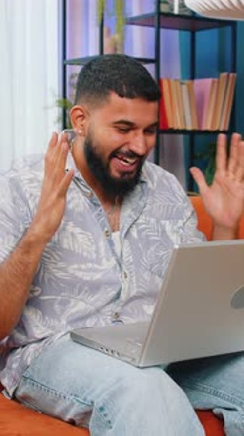 Man on Sofa Celebrates Success on Laptop