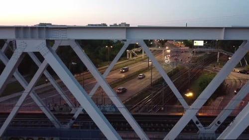 Aerial drone footage of a bridge while trains pass by on a sunset in Warsaw Poland with a city scape