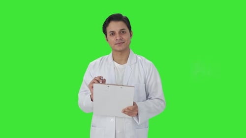 Happy Indian scientist writing observations Green screen