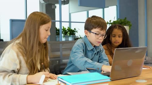 Diverse Happy School Kids Using Laptop Computer Together in Classroom Back to School