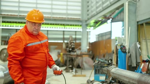 Man in Orange Jumpsuit Holding Industrial Equipment Controller