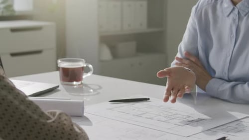 Close Up of Female Architects Discussing Technical Blueprint at Office Desk