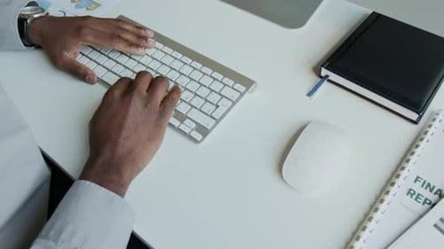 Ansicht von oben auf Hands of Black Manager, der am Bericht am Computer arbeitet