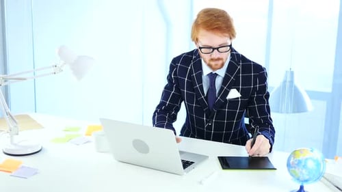 Man Using Laptop and Stylus in Office
