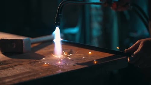 Blacksmith Heating Metal Bar with Torch in Workshop