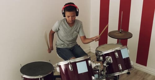 Boy Plays Drums with Headphones in Bedroom