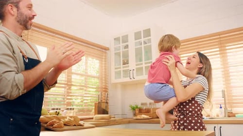Child Dancing on Kitchen Island with Family